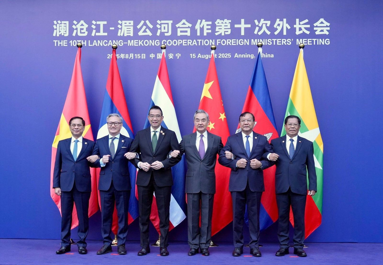 A group of men in suits standing in front of flags